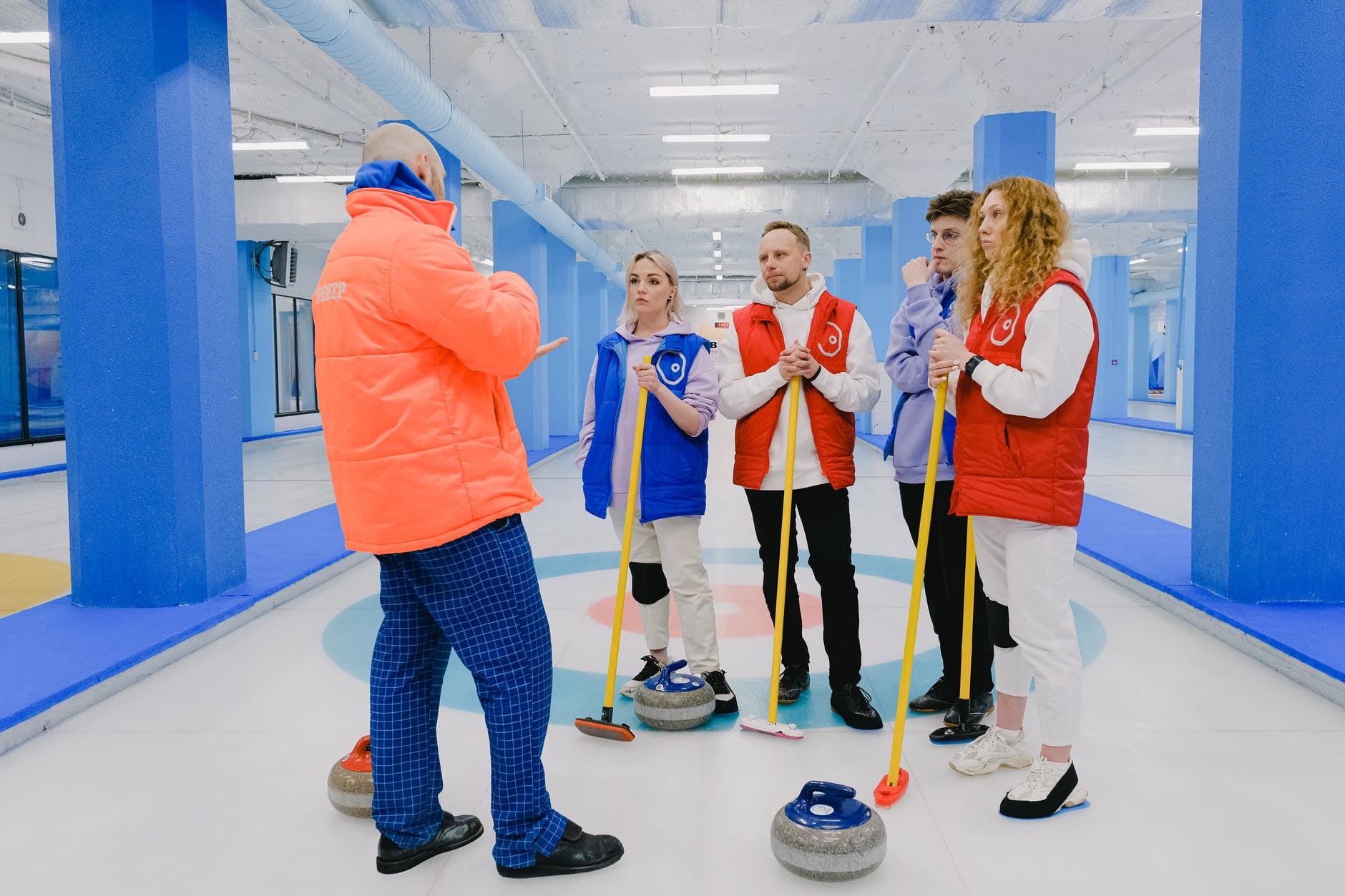curling team standing band talking with trainer on ice rink