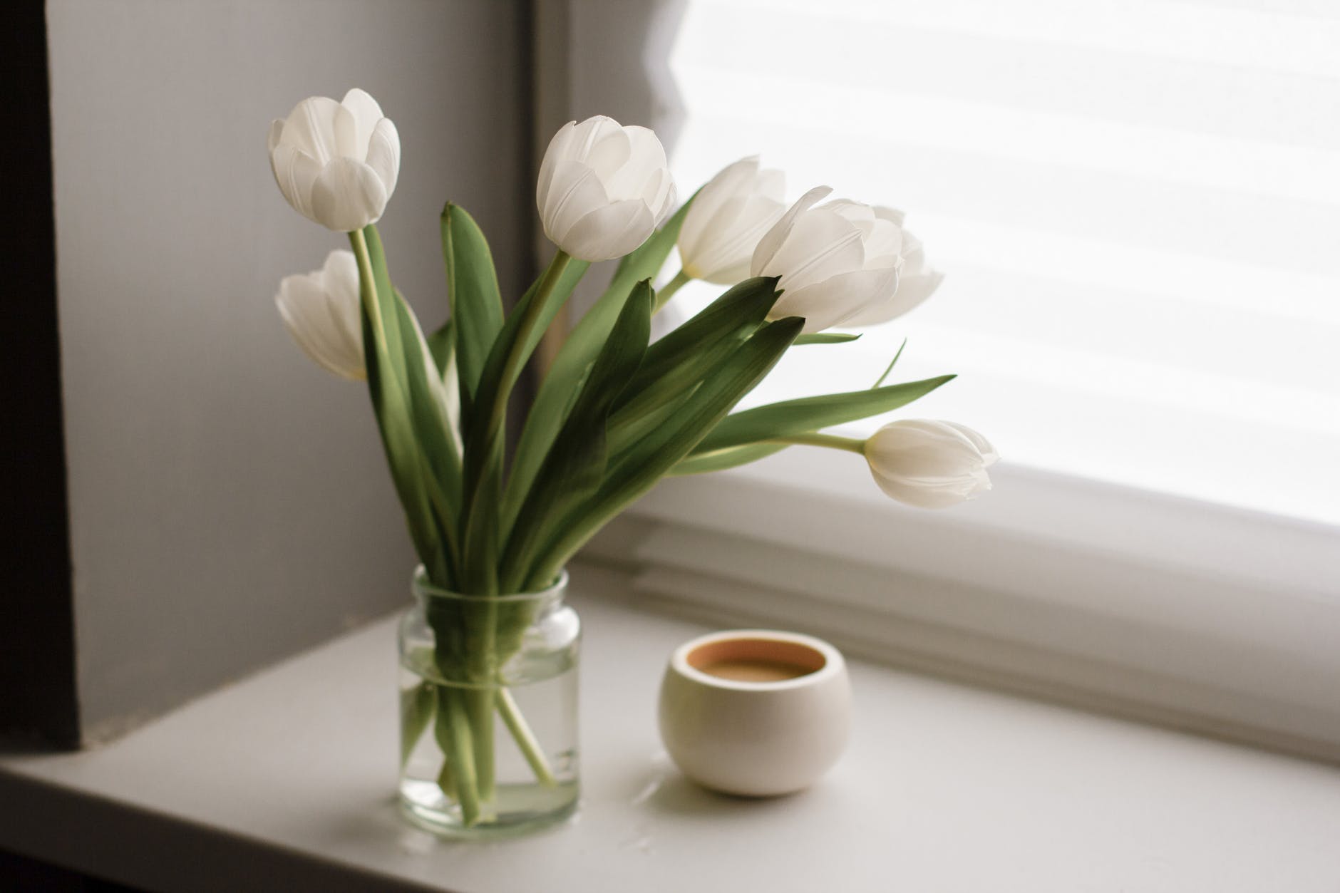 bouquet on windowsill near cup of coffee