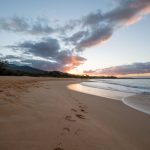 sandy beach with footprints across waving sea